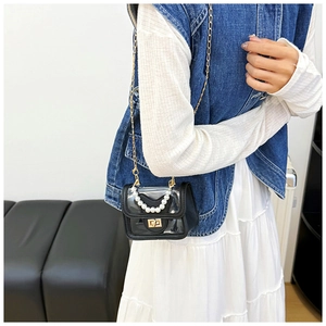 Detail of transparent PVC mini bag with pearl handle and golden chain strap on a model