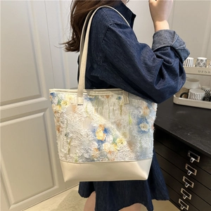 Floral fabric tote bag with cream leather trim shown on shoulder in a casual setting
