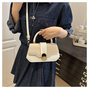 Detail of white leather and straw patchwork handbag with a golden circular metal lock