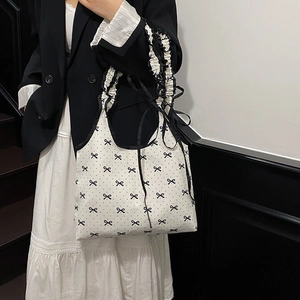 Polka dot canvas tote bag with black bow print and ruffled handle shown on a model