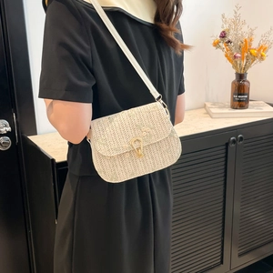 Woven straw crossbody bag with floral embroidery and gold metal clasp in soft beige