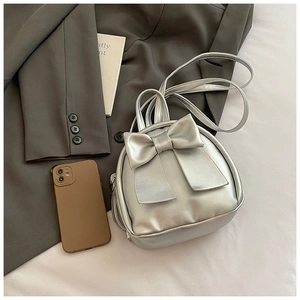 Detailed view of a silver mini bow backpack with metallic PU texture on a dark grey blazer