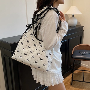 Shoulder bag with bow prints and ruffled straps for women shown in a home setting