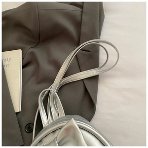 Detail of silver metallic textured backpack straps styled with a grey blazer outfit