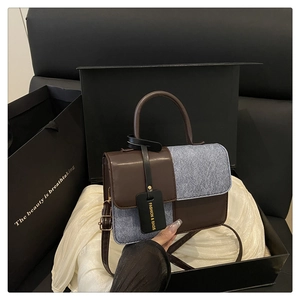 Detail of contrast stitching brown leather and blue denim texture on luxury handbag