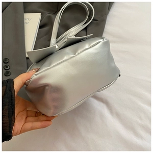 Detail of silver metallic handbag with large bow decoration and polished PU leather finish