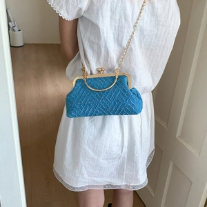 Detail of royal blue tweed handbag featuring gold metal frame and chain strap for luxury style
