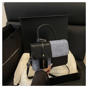 Detail of color-block tote bag with leather and denim texture in a luxury gift box