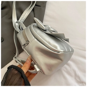 Detailed view of silver metallic mini backpack with large bow and side zipper closure