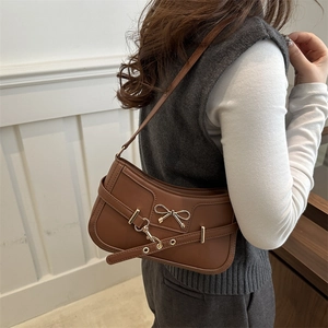 Brown leather underarm bag with a metal bow buckle and slim shoulder strap for daily commuting