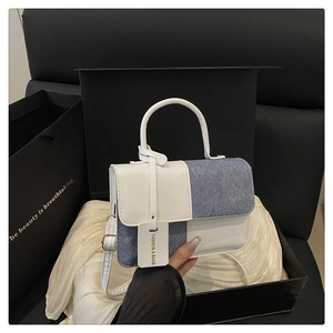 Detailed view of color-block tote bag in premium beige leather and blue denim texture