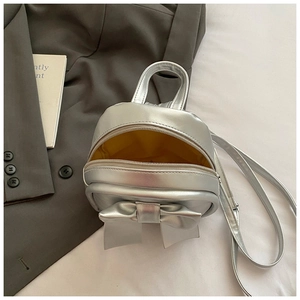 Detail of silver metallic backpack with bow decoration and bright yellow inner lining