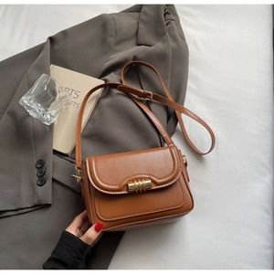Nahaufnahme der karamellbraunen Ledertasche mit goldenem Zylinderverschluss und Riemen