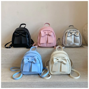 Bow knot mini backpacks in five pastel colors arranged on stone steps