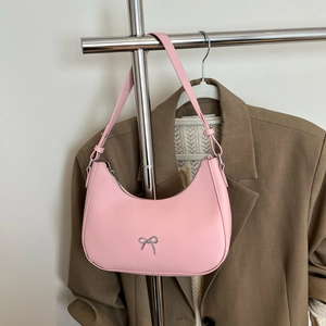 Detailed view of pink crescent shoulder bag featuring silver metal bow and matte leather