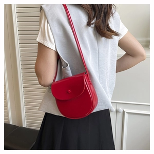Detailed back view of a bright red saddle bag on model with smooth leather texture