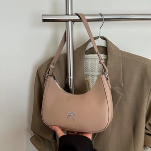 Detail of beige half-moon shoulder bag with silver bow accent and adjustable strap