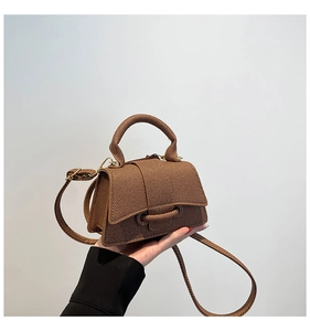 Detail of a brown woven texture handbag with a unique curved base and top handle