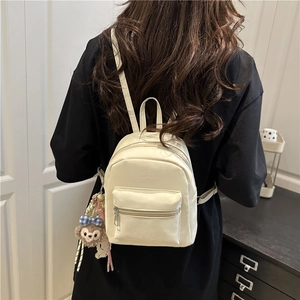 Minimalist cream white mini backpack shown on model in a cozy indoor setting