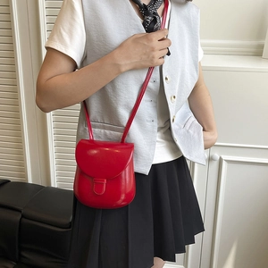 Minimalist red leather saddle bag worn by a model in a modern home setting