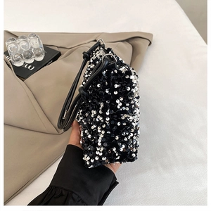 Close-up of shimmering silver sequins on black fabric and leather strap of shoulder bag
