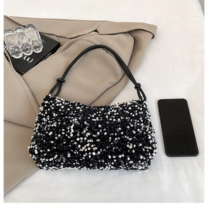 Detailed view of the black sequined handbag texture with silver accents and knotted strap