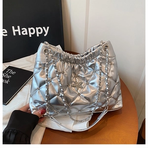 Close-up of silver quilted tote bag featuring a star emblem and metal chain strap