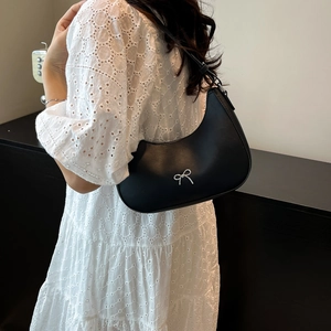 Chic black crescent hobo bag with silver bow detail on an elegant white lace dress
