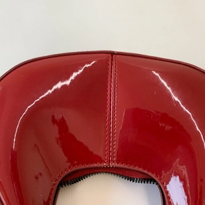Détail macro du sac en cuir verni rouge vif avec double couture de haute précision