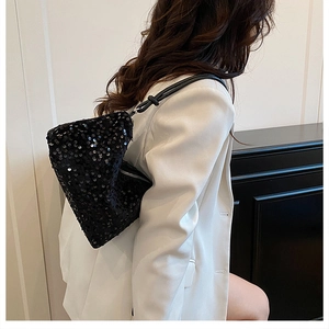 Side view of a black sequin shoulder bag on a model showing the shiny party texture