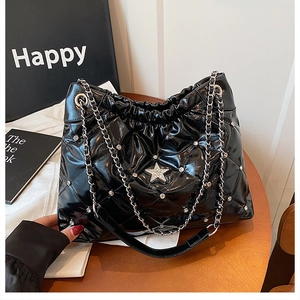 Detail of black quilted patent leather tote bag with star rhinestone and chain strap