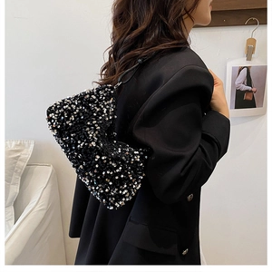 Close-up of stylish sequin hobo bag with black leather handle shown on a model
