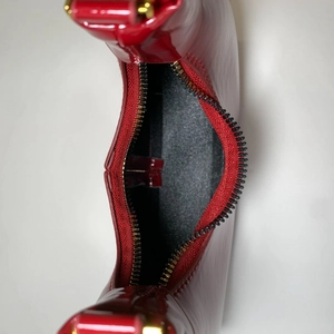 Vue détaillée du sac à main en cuir verni rouge avec fermeture éclair et doublure interne