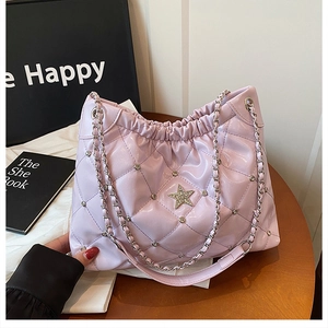 Detail of lavender quilted chain bag with diamond star and metal studs on a wooden table