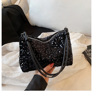 Close-up of stylish black sequin handbag with metallic zipper and knotted leather handles