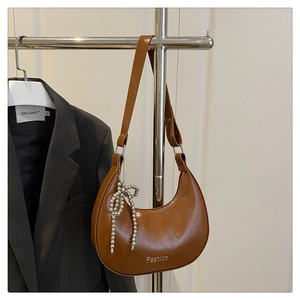 Détail du sac hobo marron avec nœud en perles et logo Fashion sur fond de veste de costume