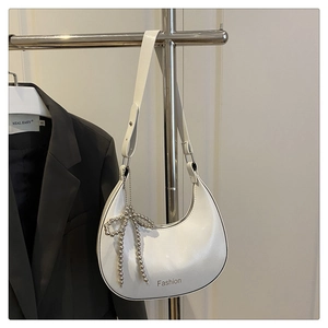 Détail du sac hobo blanc avec inscription Fashion et pendentif noeud argenté