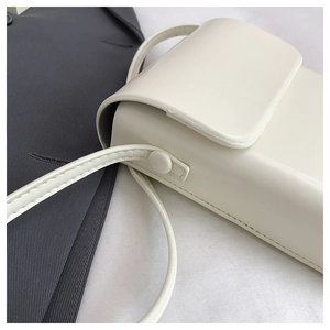 Close-up detail of cream vertical crossbody phone bag with smooth leather and side button