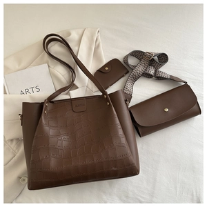 Close-up of three-piece brown tote set with crocodile embossing and woven strap
