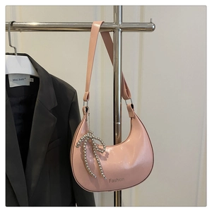 Détail du sac hobo en cuir verni rose avec nœud perlé et logo Fashion gravé