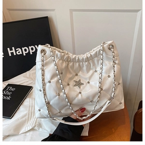 Close-up of quilted white leather bag with silver studs and star sequin details