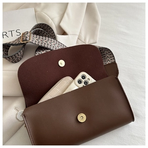Detail view of coffee brown crossbody bag with colorful woven strap and magnetic closure