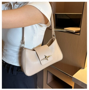 Detail of milk tea color shoulder bag with star metal clasp on a white polo shirt