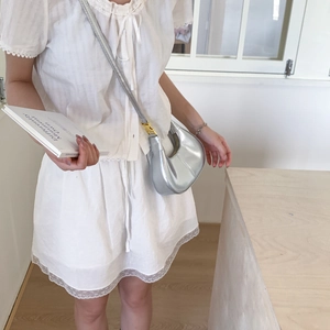 Sac hobo argenté métallisé avec boucles dorées présenté dans un décor d'intérieur chic