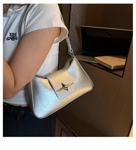 Detail of silver metallic underarm bag with star-shaped buckle and leather shoulder strap