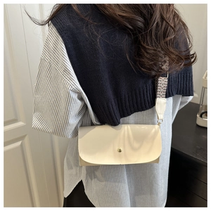 Beige crossbody bag with wide geometric strap shown from a model's side view
