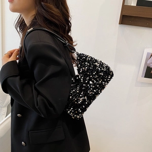 Chic black sequin crossbody bag with chain strap worn by a model in a black suit
