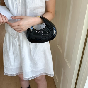 Sac à main croissant en cuir verni noir brillant avec fermeture éclair dorée style épuré