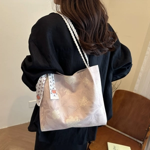 Sac fourre-tout rose à motif floral avec bandoulière tressée porté par un mannequin