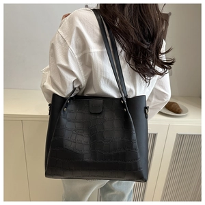 Macro view of black tote bag showing crocodile pattern texture and shoulder strap detail